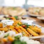 An assortment of tasty appetizers including schnitzel, served on eco-friendly bamboo plates at a festive gathering.