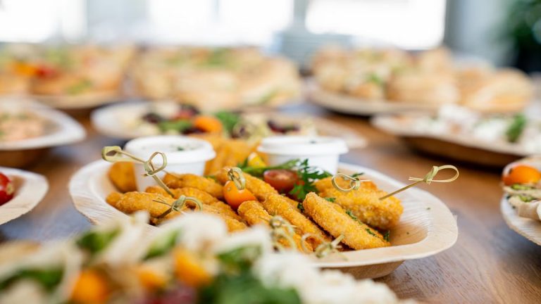 An assortment of tasty appetizers including schnitzel, served on eco-friendly bamboo plates at a festive gathering.
