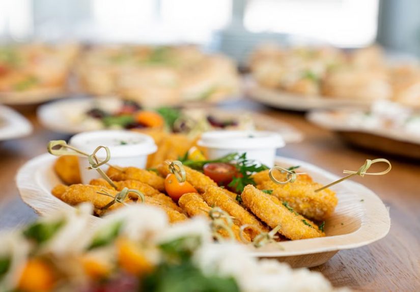 An assortment of tasty appetizers including schnitzel, served on eco-friendly bamboo plates at a festive gathering.