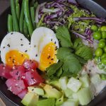 A delicious and colorful poke bowl featuring eggs, vegetables, and fresh produce, perfect for a healthy meal.