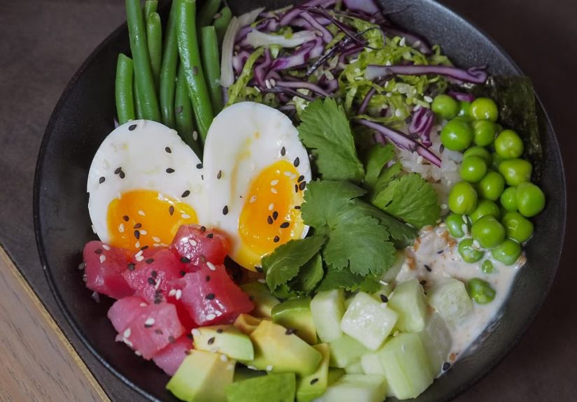 A delicious and colorful poke bowl featuring eggs, vegetables, and fresh produce, perfect for a healthy meal.